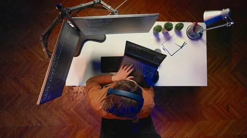It admin using multimonitor PC setup and laptop to finish tasks, aerial shot Stock Photos