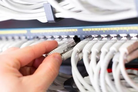 IT consultant connects a network cable into switch in datacenter Stock Photos