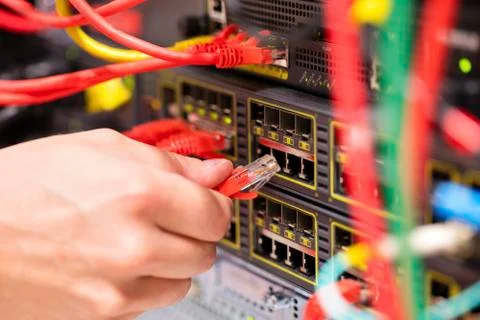 IT consultant connects a network cable into switch in datacenter Stock Photos