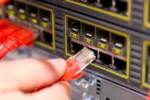 IT consultant connects a network cable into switch in datacenter Foto stock