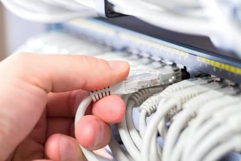 IT consultant connects a network cable into switch in datacenter Stock Photos