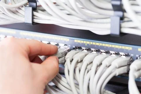 IT consultant connects a network cable into switch in datacenter Stock Photos