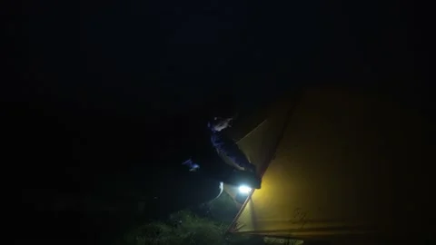 It is a dark night, a man with a lantern goes to the tent and goes inside Stock Footage 238354791