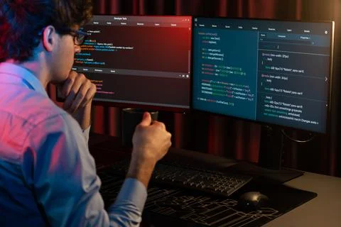 IT developer concentrating software while drinking coffee at neon light. Gusher. Stock Photos