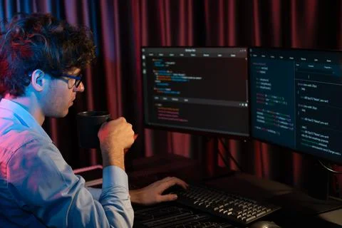 IT developer concentrating software while drinking coffee at neon light. Gusher. Stock Photos