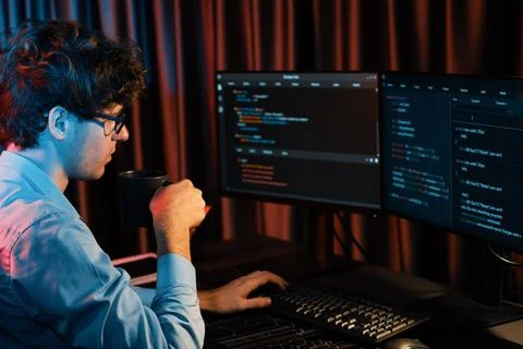 IT developer concentrating software while drinking coffee at neon light. Gusher. Stock Photos