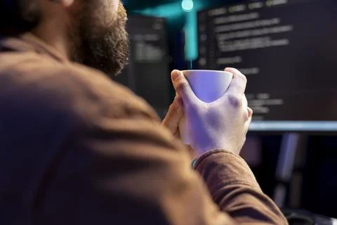 IT developer drinking coffee while fixing vulnerabilities in software Stock Photos