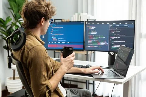 IT developer holding coffee cup with looking online software on pc. Gusher. Stock Photos