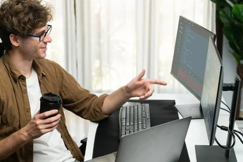 IT developer holding coffee cup with looking online software on pc. Gusher. Stock Photos