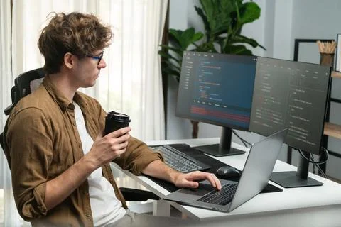 IT developer holding coffee cup with looking online software on pc. Gusher. Foto stock