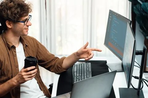 IT developer holding coffee cup with looking online software on pc. Gusher. Stock Photos