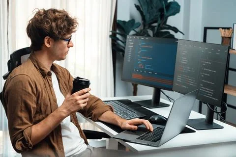IT developer holding coffee cup with looking online software on pc. Gusher. Stock Photos