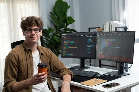 IT developer looking at camera and holding coffee cup. Gusher. Foto stock