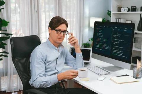IT developer looking camera, holding coffee cup with coding on pc. Pecuniary. Stock Photos