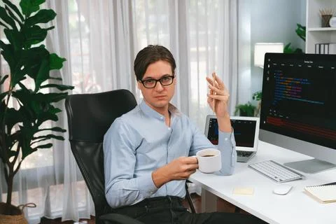 IT developer looking camera, holding coffee cup with coding on pc. Pecuniary. Stock Photos