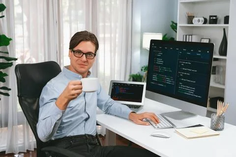 IT developer looking camera, holding coffee cup with coding on pc. Pecuniary. Stock Photos