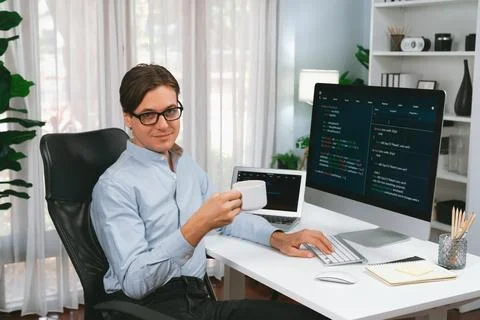 IT developer looking camera, holding coffee cup with coding on pc. Pecuniary. Stock Photos