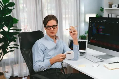 IT developer looking camera, holding coffee cup with coding on pc. Pecuniary. Stock Photos