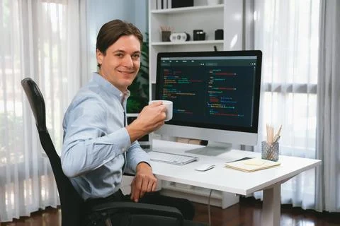 IT developer looking camera, holding coffee cup with coding on pc. Pecuniary. Stock Photos