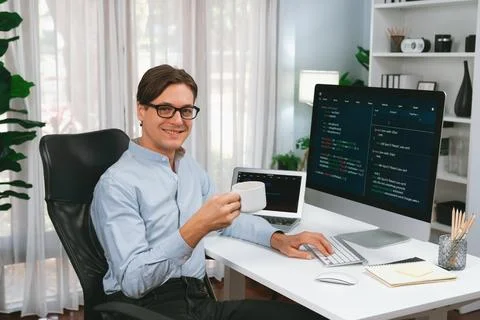 IT developer looking camera, holding coffee cup with coding on pc. Pecuniary. Stock Photos