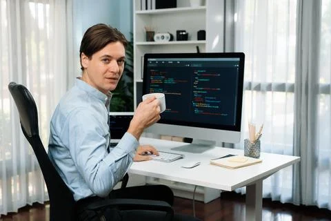 IT developer looking camera, holding coffee cup with coding on pc. Pecuniary. Stock Photos