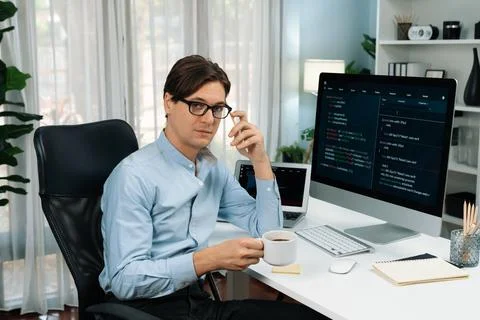 IT developer looking camera, holding coffee cup with coding on pc. Pecuniary. Stock Photos