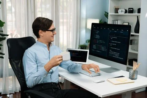 IT developer looking camera, holding coffee cup with coding on pc. Pecuniary. Stock Photos