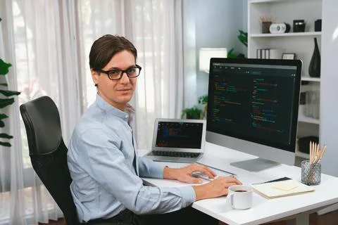 IT developer looking camera while working on pc and laptop. Pecuniary. Stockfoto's