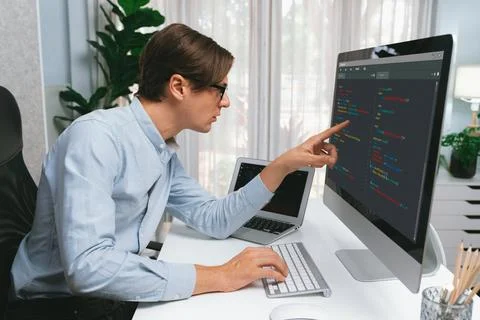 IT developer pointing on coding software on pc comparing laptop. Pecuniary. Foto stock