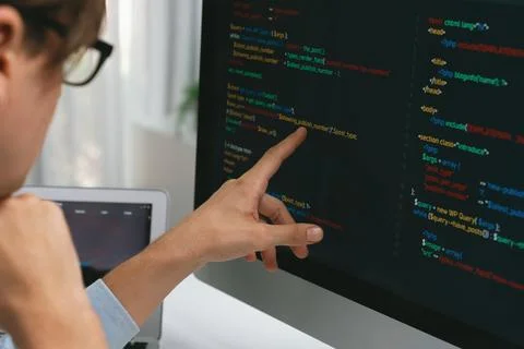 IT developer pointing on coding software on pc comparing laptop. Pecuniary. Foto stock