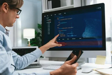 IT developer pointing on coding software on pc comparing laptop. Pecuniary. Stockfoto's
