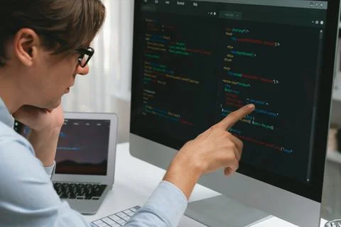 IT developer pointing on coding software on pc comparing laptop. Pecuniary. Foto stock