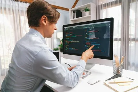 IT developer pointing on coding software on pc comparing laptop. Pecuniary. Stock Photos