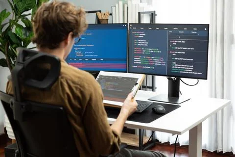 IT developer reading coding on document paper software with screens. Gusher. Stock Photos