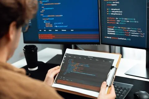 IT developer reading coding on document paper software with screens. Gusher. Stock Photos