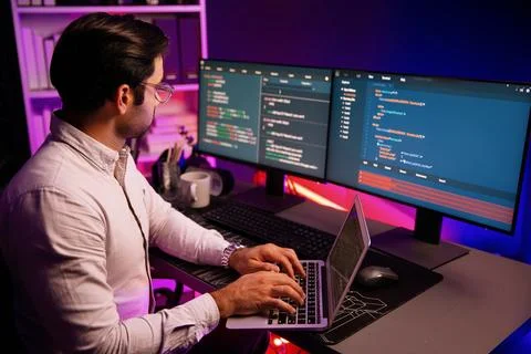 IT developer working laptop to search code system at neon light office. Surmise. Stock Photos