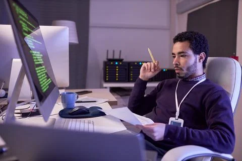 IT developer working at night writat desk in office Stockfoto's