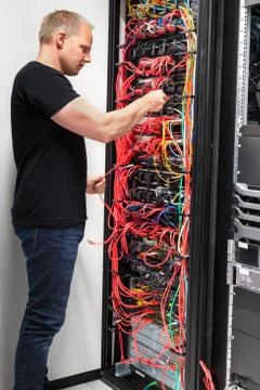 IT Engineer Checking With Network Cables Connected To Servers Stock Photos
