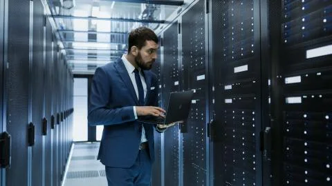 IT Engineer in Data Center Stands Before Server Rack Cabinet Working on His L Stock Photos
