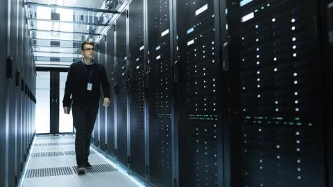 IT Engineer Holding Notebook and Walking Through Data Center Full of Working  Foto stock