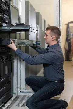 IT Engineer installs equipment to rack in datacenter Stock Photos