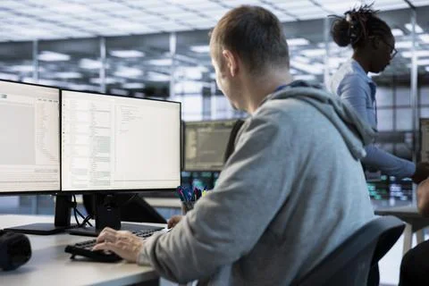 IT engineer looking at PC screen, working in network security data center Stock Photos