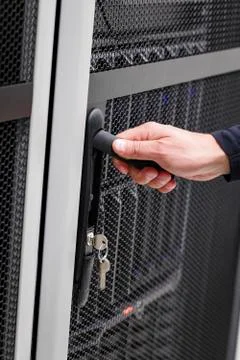 IT engineer opens door to server rack in datacenter Stock Photos