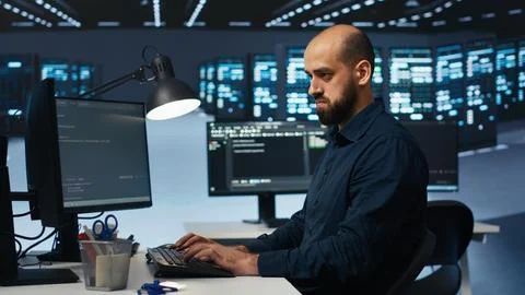 IT engineer overseeing server room, running code, troubleshooting servers Stock Photos
