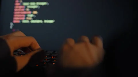 An IT engineer rapidly types complex algorithms on a keyboard refining an ar Stock Footage 334546150