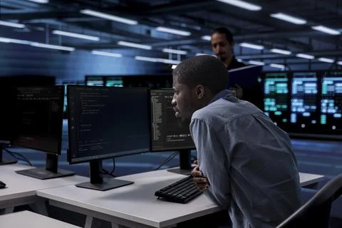 IT engineer in server room facility confused by errors on screen Stock Photos