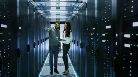 IT Engineer Shows Working Data Center / Server Room to Female Chief Engineer  Stock Photos
