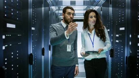 IT Engineer Shows Working Data Center / Server Room to Female Chief Engineer  Stock Photos