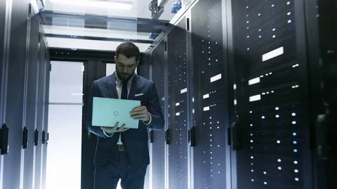 IT Engineer Walking in Data Center full of Rack Servers, He Holds Laptop  库存影片 73666375