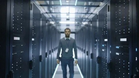 IT Engineer Walks Into Focus  and Smiles in Data Center Full of Rack Servers. Video stock 73876131